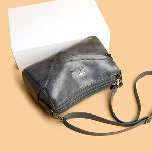 Sac bandoulière cylindrique en cuir lavé gris foncé avec plusieurs zips et logo kangourou
