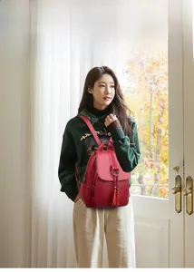 Close-up of retro dark red leather backpack featuring tassel pendant and metallic ring