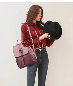 Close-up of pink leather backpack with tassel pendant and woven metallic buckle details