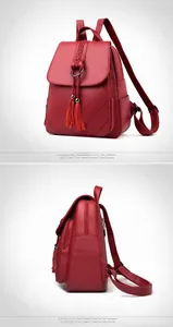 Detail view of burgundy pebble leather backpack with tassel charm and side zipper pockets