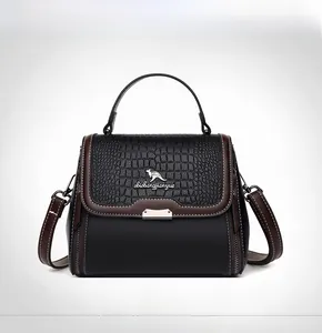 Front view of black handbag with crocodile pattern flap and metal handle details