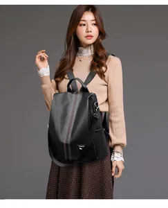 Close-up of black lychee grain leather backpack with stylish red and white stripe detail