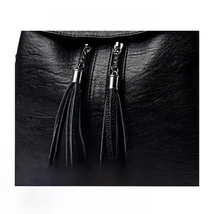 Close-up of black lychee grain leather bag with metal zipper and dual tassels
