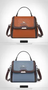 Detail of crocodile embossed leather handbag showing kangaroo logo and metal zipper accents