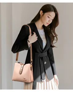 On-model view of a pink leather bucket bag with golden Kangaroo logo and metal lock