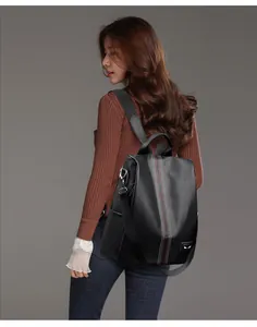 Side view of black lychee grain leather backpack with stripe and eye patch detail