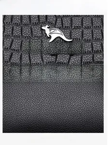 Detail of black crocodile texture and pebble leather with silver kangaroo emblem