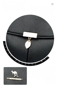Détails du pendentif doré et du logo sur le sac à dos en cuir noir grainé