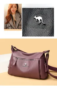 Dettaglio della borsa a tracolla viola in pelle martellata con logo a canguro