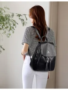 Detail of black faux leather backpack with metallic logo, tassels and side zipper pocket