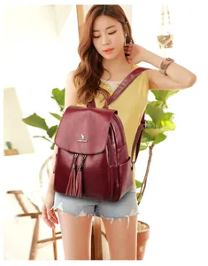 Close-up of burgundy leather backpack featuring metallic kangaroo logo and twin tassel zippers