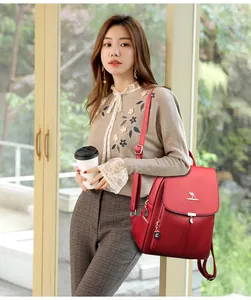 Détail d'un sac à dos rouge en cuir texturé avec logo kangourou et pendentif en feuille