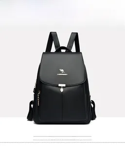 Détail du sac à dos en cuir noir avec logo kangourou doré et pendentif en forme de feuille