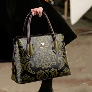 Elegante zwarte handtas met olijfgroen bloemmotief en luxe lederen handvaten