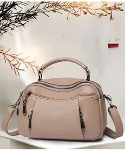 Detail view of khaki pleated boston bag with smooth zipper and sturdy top handles