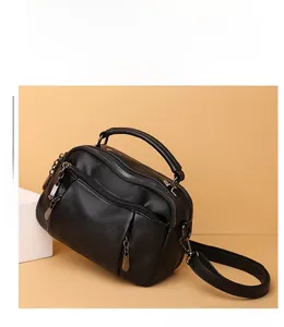 Detail of black litchi texture leather Boston bag with silver zippers and top handle