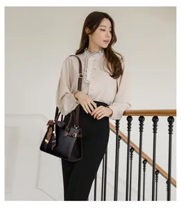 Detalle de bolso negro en cuero grabado con pañuelo de seda y correa de hombro ajustable