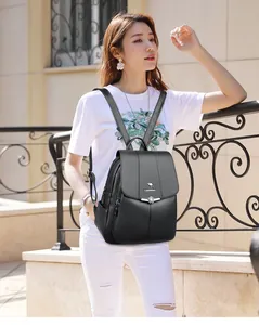 Detalle de mochila negra en cuero lichi con logo de canguro metálico y cierre plateado