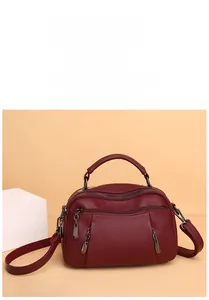 Detail of wine red Boston handbag featuring pebble texture, dual zippers and metal charms