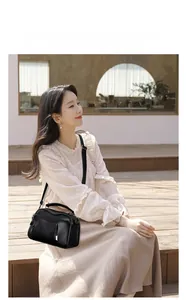 Detail of black pebbled leather Boston bag with multiple zippers and adjustable strap