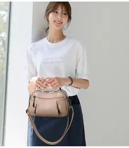 Detail of beige lychee grain leather handbag with multi-zipper pockets and shoulder strap