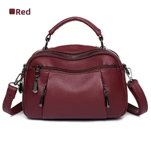 Detailed close-up of the red pebble-texture leather and dark metal zipper on the handbag