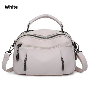 Close-up of white Boston bag with litchi texture, multi-zipper and gunmetal hardware