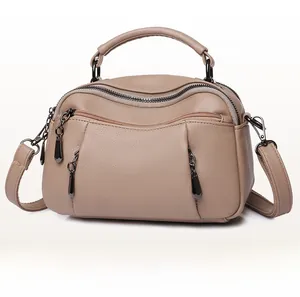 Side view of beige lychee grain leather Boston bag with multi-zipper compartments