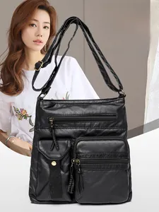 Close-up of black multi-pocket crossbody bag with metallic zippers and adjustable strap
