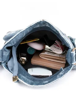 Detail view of denim texture crossbody bag showing large internal storage with zip pocket