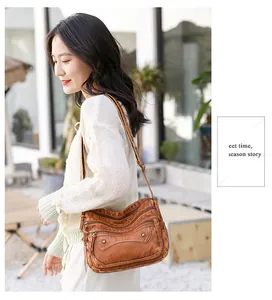 Close-up of vintage brown washed leather bag with rivet details and multiple zipper pockets
