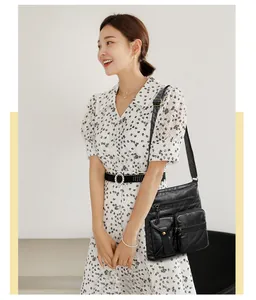 Detail view of a black multi-pocket crossbody bucket bag worn by a model in a floral dress