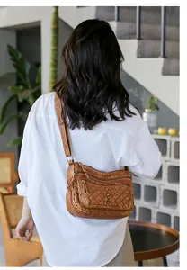 Rear view of brown washed leather crossbody bag with quilted pattern and metal rivets