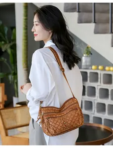 Close-up of quilted dark brown crossbody bag with metal rivets and zipper detail
