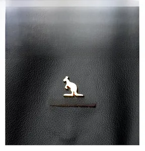 Dettaglio macro del logo dorato a forma di canguro su pelle nera martellata dello zaino
