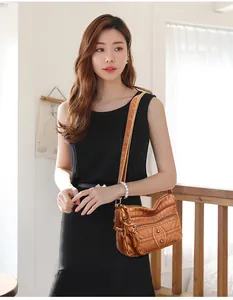 Brown washed leather crossbody bag with multiple zippers and rivets on a model