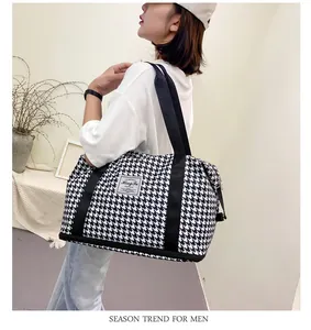 Κοντινό πλάνο τσάντας ταξιδιού με μοτίβο houndstooth και υφαντή ετικέτα μάρκας