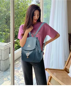 Dettaglio dello zaino in ecopelle blu con logo a canguro dorato e ciondolo a gatto