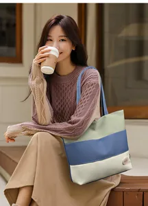 Detail of color-block canvas tote bag with pink good luck label and stripe design
