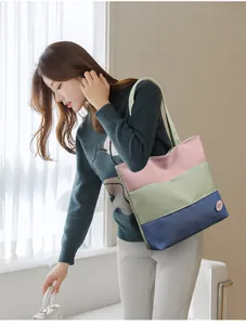 Close-up of a tricolor stitched canvas bucket bag with wide shoulder strap details