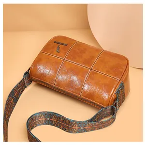 Close-up of brown barrel bag with grid stitching and bohemian colorful woven strap