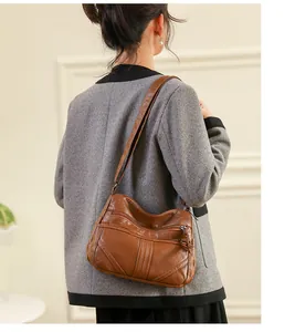 Close-up of brown washed PU leather crossbody bag with three distinct zipper pockets