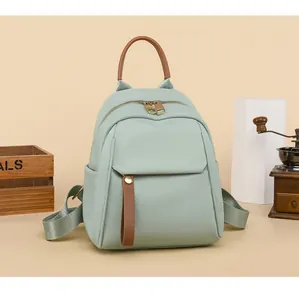 Mint green high-density oxford backpack with brown leather trim and golden metal zippers
