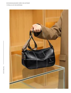 Detail of black leather barrel bag featuring white contrast stitching and ethnic strap