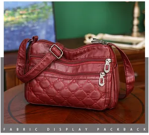 Detail van bordeauxrode PU-lederen crossbodytas met drie ritsen en gewatteerde stiksels