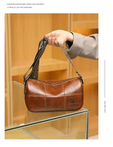 Detail of vintage brown leather barrel bag with white stitching and floral woven strap