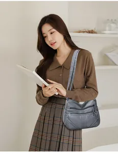 Detail of dark grey multi-pocket faux leather crossbody bag with diamond stitching