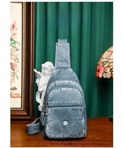 Detail of grey-blue soft leather chest bag featuring three zip pockets and snap button pouch