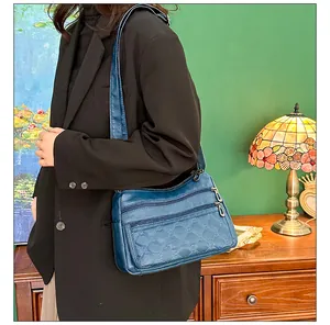 Donkerblauwe gewatteerde lederen crossbodytas met ritsen gedragen door een model