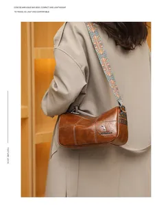 Brown leather barrel bag detail featuring embroidered strap and kangaroo metal logo